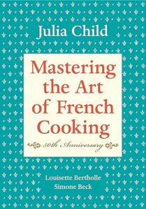 A cover of a 50th anniversary edition book titled "mastering the art of french cooking" by julia child, with contributions by simone beck and louisette bertholle, featuring a decorative patterned background.