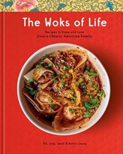 A cookbook cover titled "the woks of life: recipes to know and love from a chinese american family" by bill, judy, sarah & kaitlin leung, featuring a vibrant red background and a photo of a dish with dumplings garnished with sesame seeds and green onions.