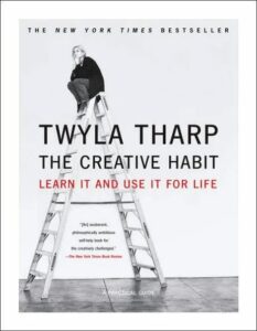 An individual sitting atop a ladder with a pensive look, against the backdrop of a book cover for "the creative habit" by twyla tharp, presenting the theme of pursuing creative understanding and application.