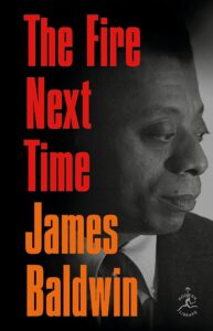 A book cover featuring the title "the fire next time" by james baldwin, displaying a profile portrait of james baldwin with a contemplative expression against a contrasting dark background, highlighted with bold red and orange lettering.