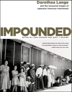 A group of people waiting, possibly at a transportation hub or for an event, with a focus on a historical context, as indicated by the book title "impounded: dorothea lange and the censored images of japanese american internment" which suggests the photograph relates to a significant period in american history.