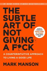 A bold orange book cover for "the subtle art of not giving a f*ck" by mark manson, proclaiming a counterintuitive approach to living a good life and noting its status as a #1 new york times bestseller.