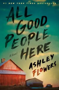 Book cover of "all good people here" by ashley flowers, featuring a large red barn against a green, brush-stroke style background with yellow text overlay.