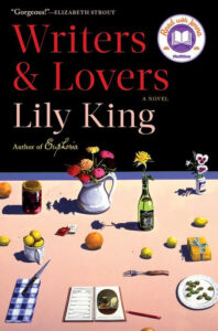 Book cover of "Writers & Lovers" showing a table with flowers, fruit, books, bottles, and stationery.