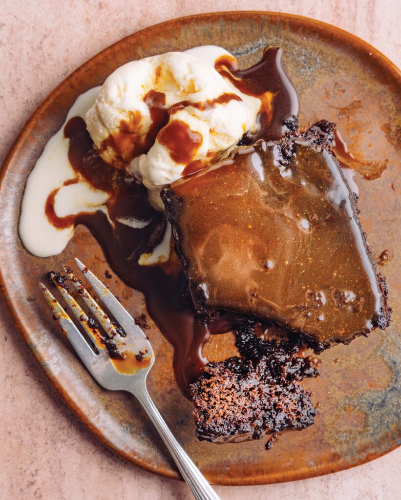 A plate with chocolate cake, vanilla ice cream, chocolate sauce, and a fork.