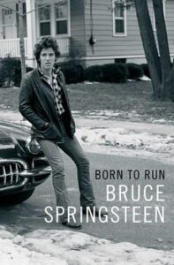 A man leans against a car on a snowy street; text reads "Born to Run Bruce Springsteen.