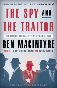Book cover for "The Spy and The Traitor" with silhouettes of men in hats and trench coats against a blue background.