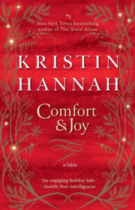 A red book cover for "Comfort & Joy" by Kristin Hannah, decorated with golden holiday branches and lights.