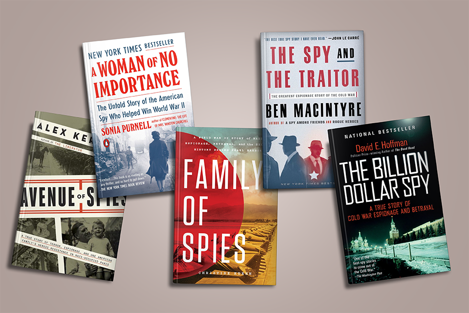 Five spy-themed books with various covers are arranged on a light brown surface.
