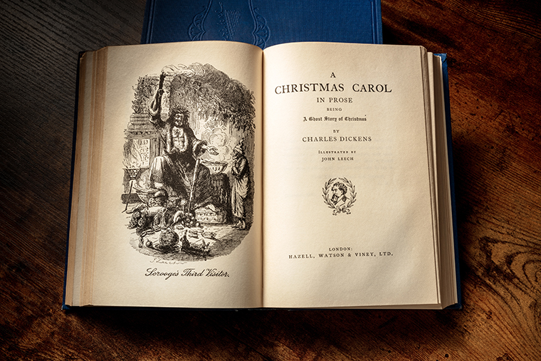 An open book shows "A Christmas Carol" by Charles Dickens with an illustration and title page visible.