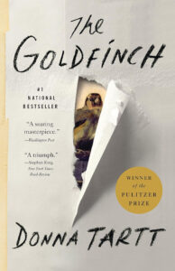 Book cover of "The Goldfinch" by Donna Tartt, with a torn paper revealing a small bird painting underneath.