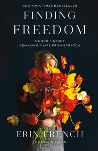 A woman holding a large bouquet of orange and yellow flowers on the cover of "Finding Freedom" by Erin French.
