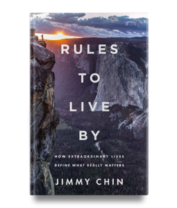 Book cover of "Rules to Live By" by Jimmy Chin, featuring a mountain landscape at sunrise with a figure on a cliff.