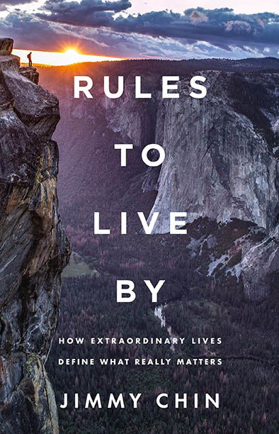 A person stands on a cliff edge at sunset with mountains in the background; text reads "Rules to Live By" by Jimmy Chin.