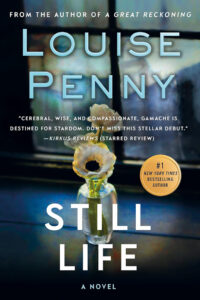 A white flower in a small bottle on a dark background, with “Still Life” by Louise Penny as the book title.