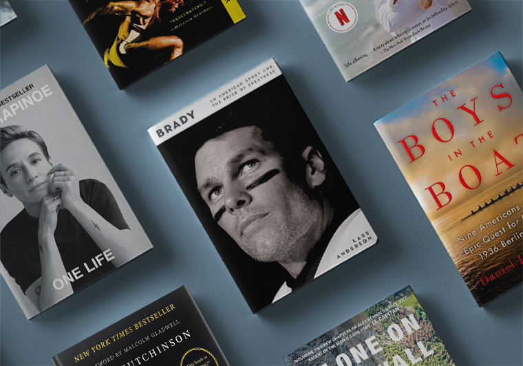 Flat lay of several hardcover books including biographies of Megan Rapinoe, Tom Brady, and The Boys in the Boat.
